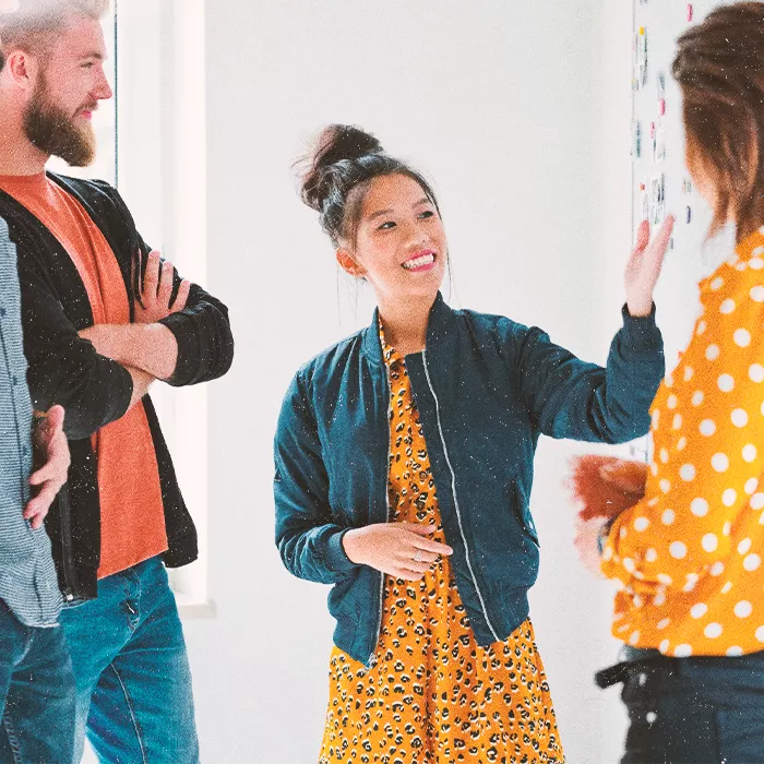 Smiling woman presenting to her colleagues by a whiteboard