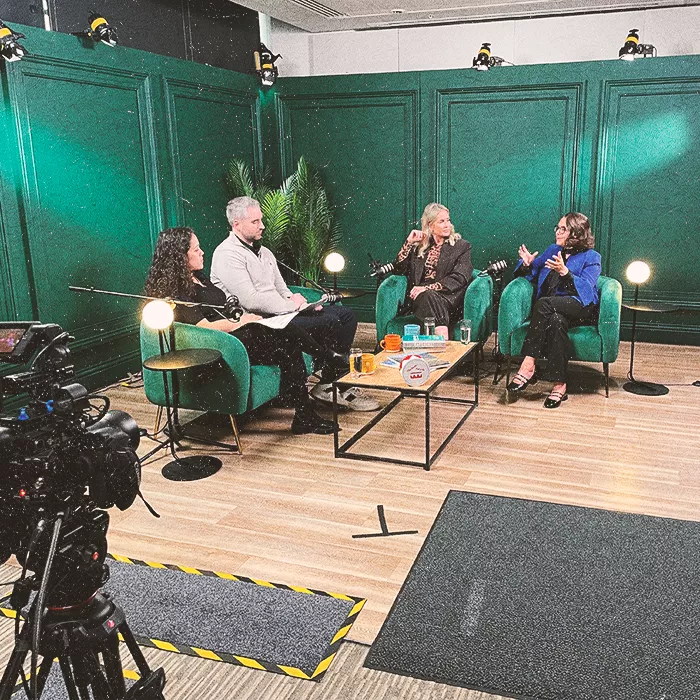 Four people sitting in green chairs discussing