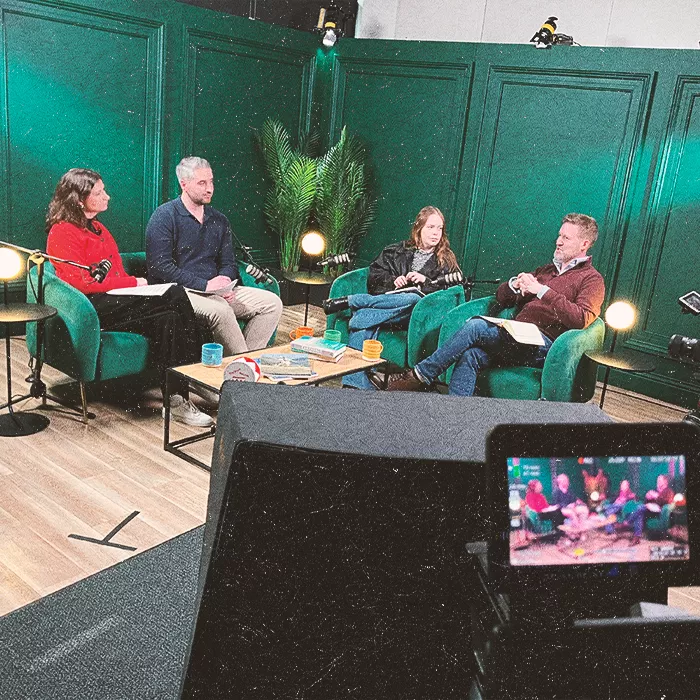 Four people sitting in green chairs discussing