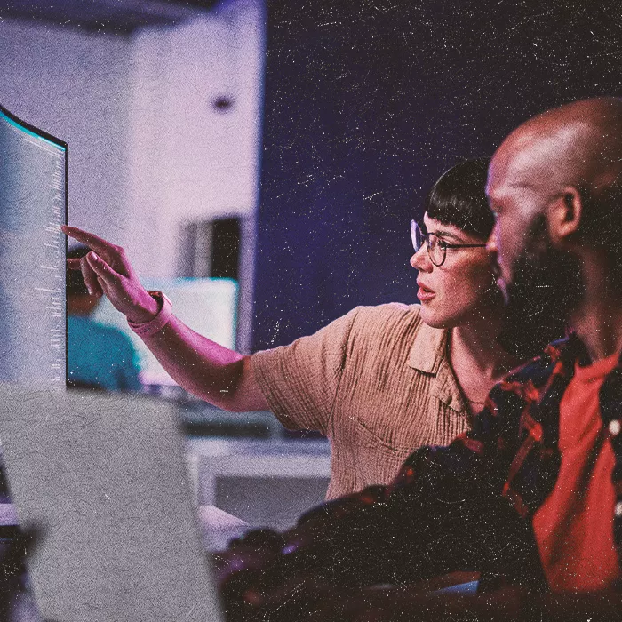 Two people working together by a screen