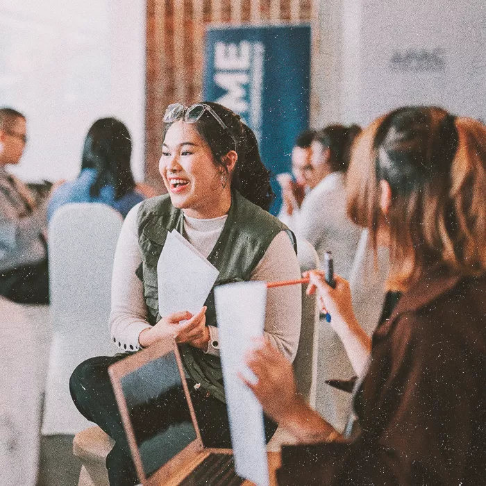 Woman in group discussion pointing to her paper and smiling