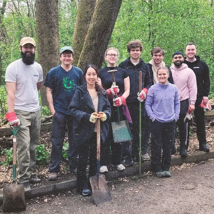 Nine people standing with garden tools smiling at the camera