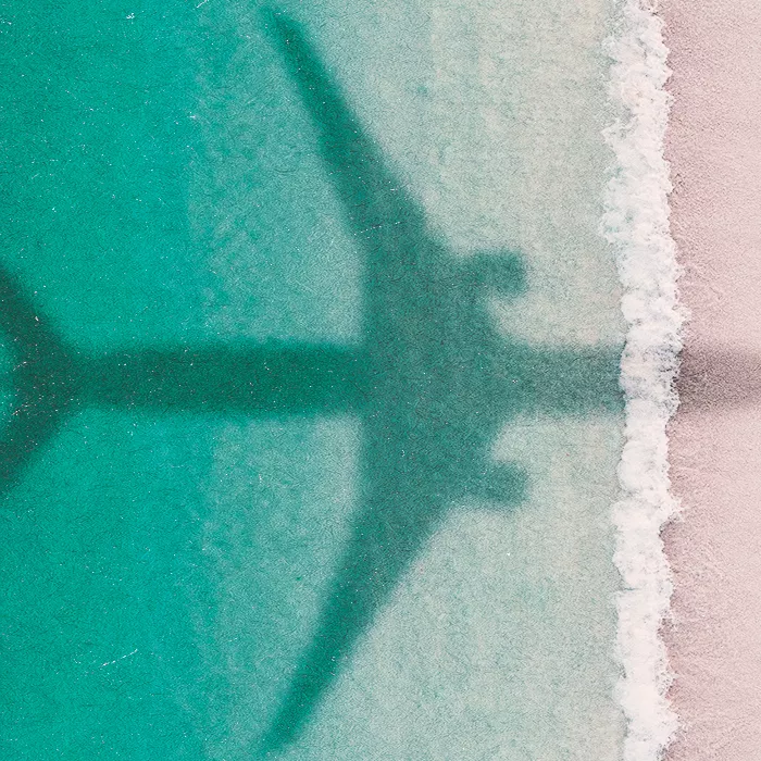 Shadow of an airplane showing on the beach and sea