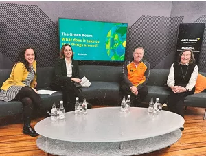 Four people sitting on sofa with a TV in the background