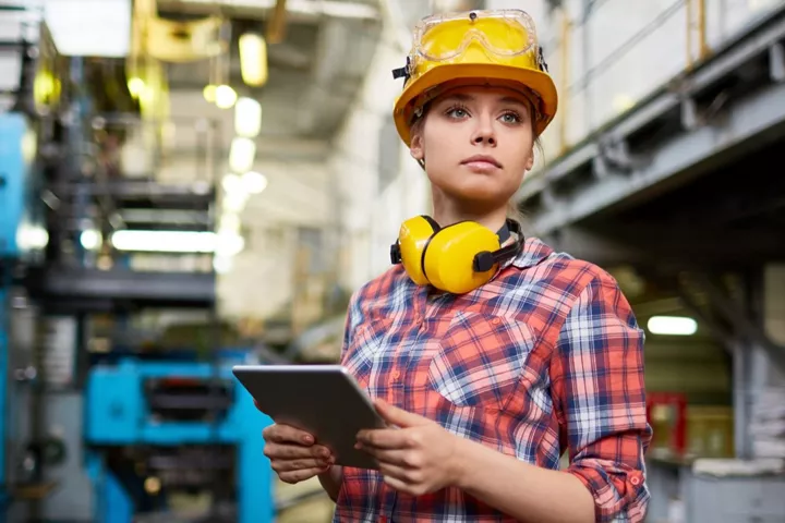 Žena oblečená do stavebních ochranných pomůcek.