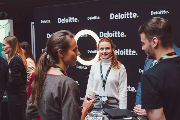 Lidé se baví u stánku Deloitte na networkingové akci