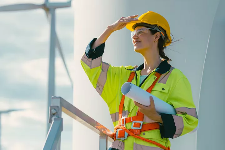 Female engineer inspecting modern wind turbines