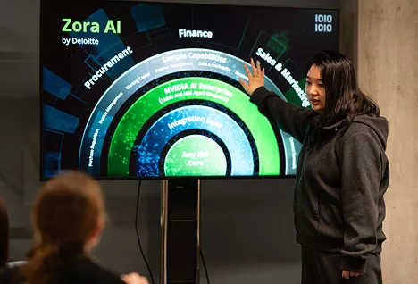 Woman presenting Zora AI by Deloitte pointing at a screen
