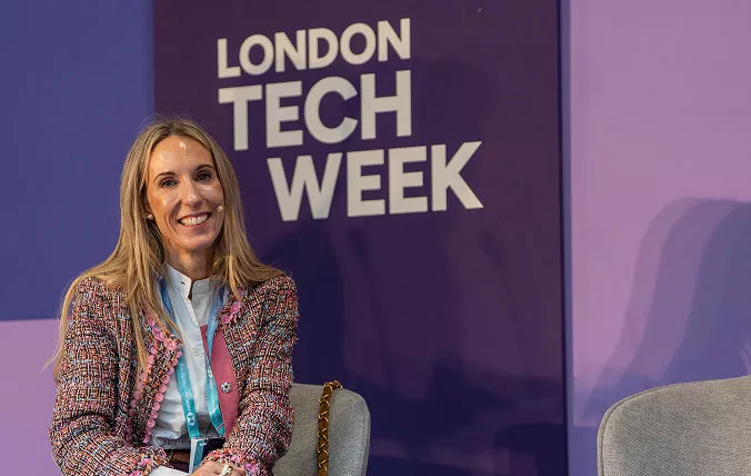 Woman smiling at the camera with London tech Week sign in the background
