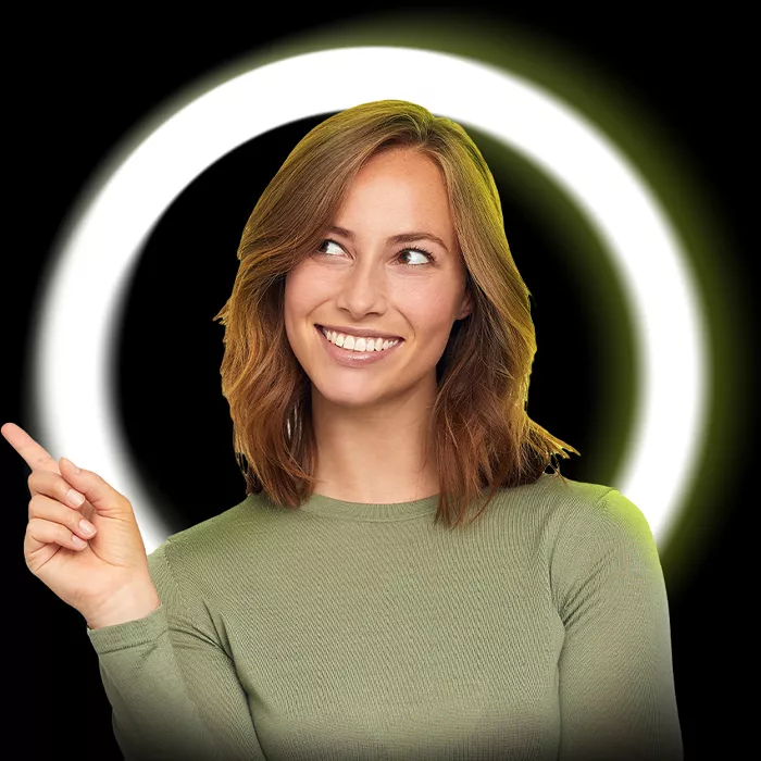 Usmívající se žena v zelené halence ukazuje prstem doleva před černo-zeleným kruhovým světelným pozadím