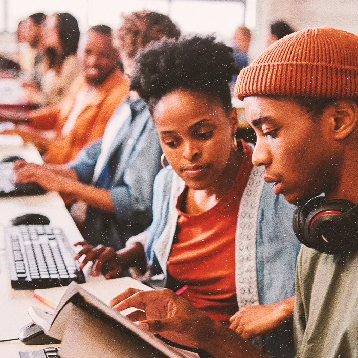 Two people reading the same book in a classroom