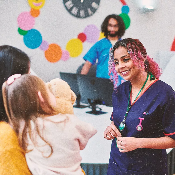 Smiling nurse facing camera talking to woman and child
