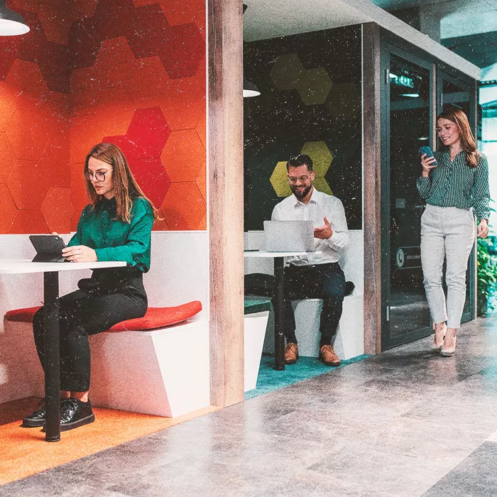 Two people sitting, and one walking in an open working environment