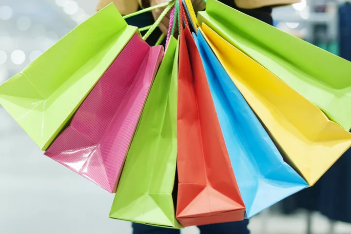 Person inj shopping center holding colorfull shopping bags.