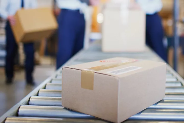 Paper box at the end of conveyor band. In blurred background other boxes are being loaded..