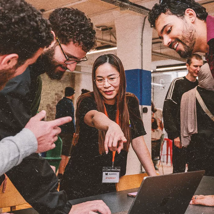 Four students discussing standing around a laptop