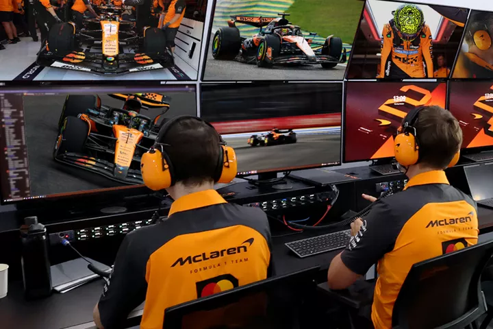 McLaren Racing: Race team engineers watch multiple monitors in the garage during a Formula 1 event.
