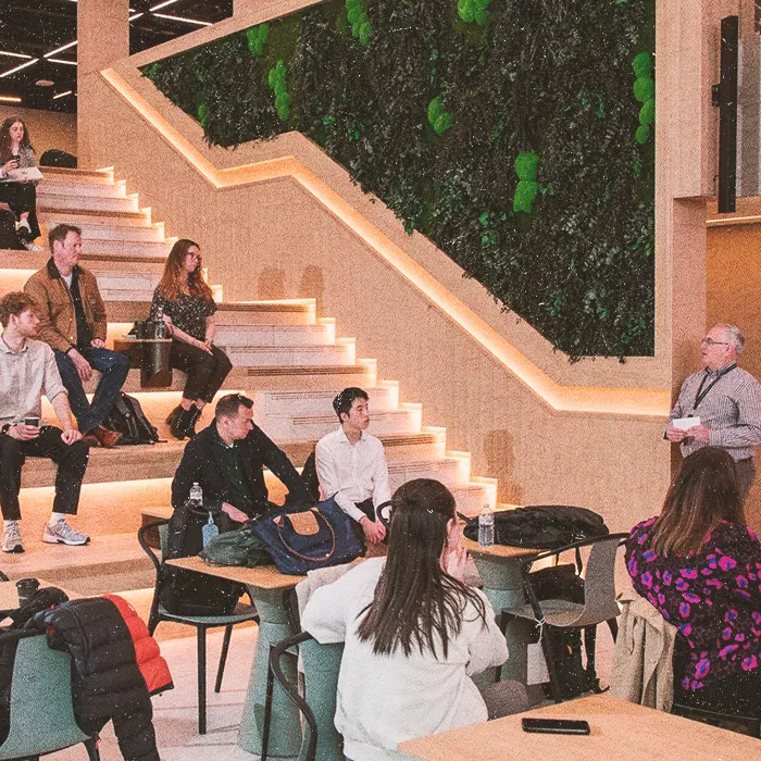 People sitting in stairs listening to a speaker