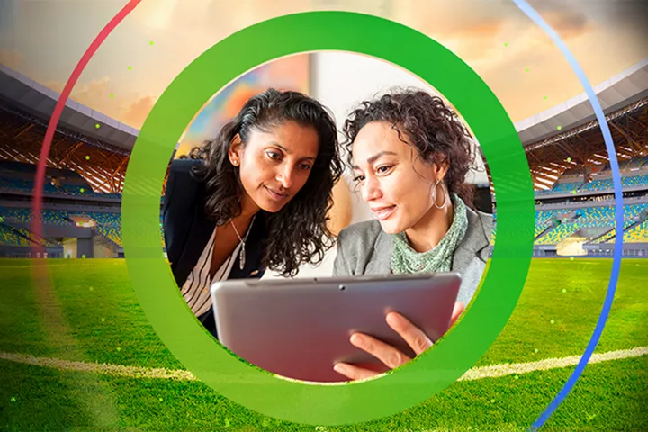 Two people reviewing a laptop in a stadium with a green ring overlay
