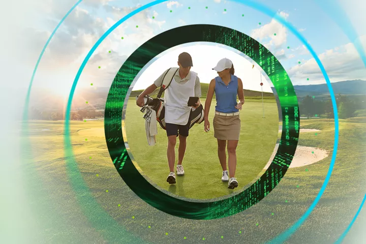 Two women golfers walk the course carrying clubs.