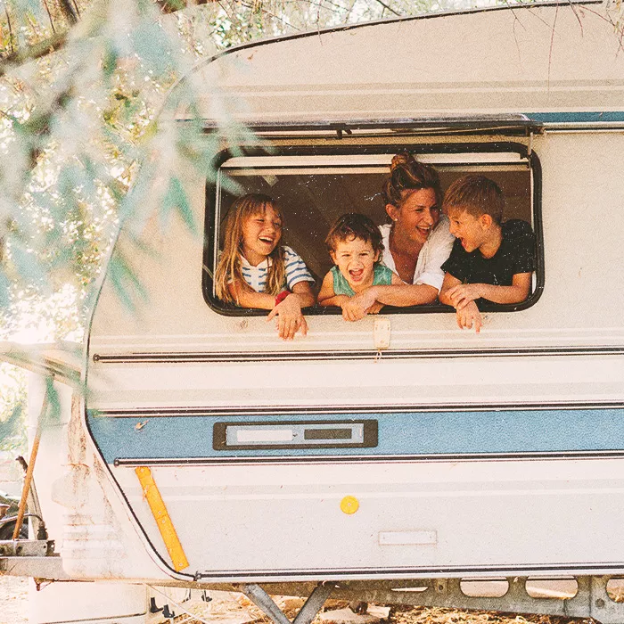 Three kids and a woman looking out through camping van window